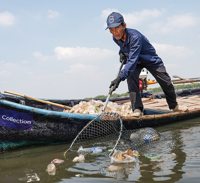 Collector pulling plastic from the water with a net