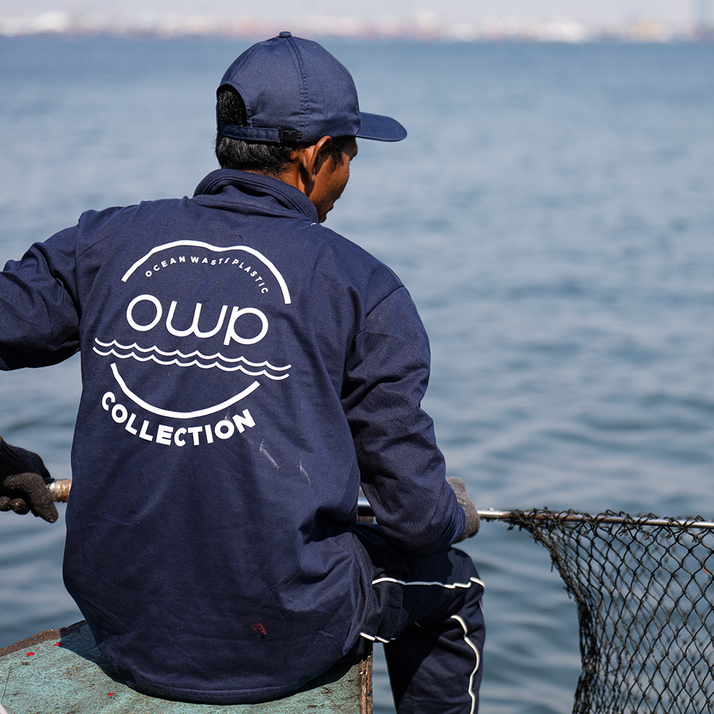 Collector in an OWP Collection jacket holding a net on the water