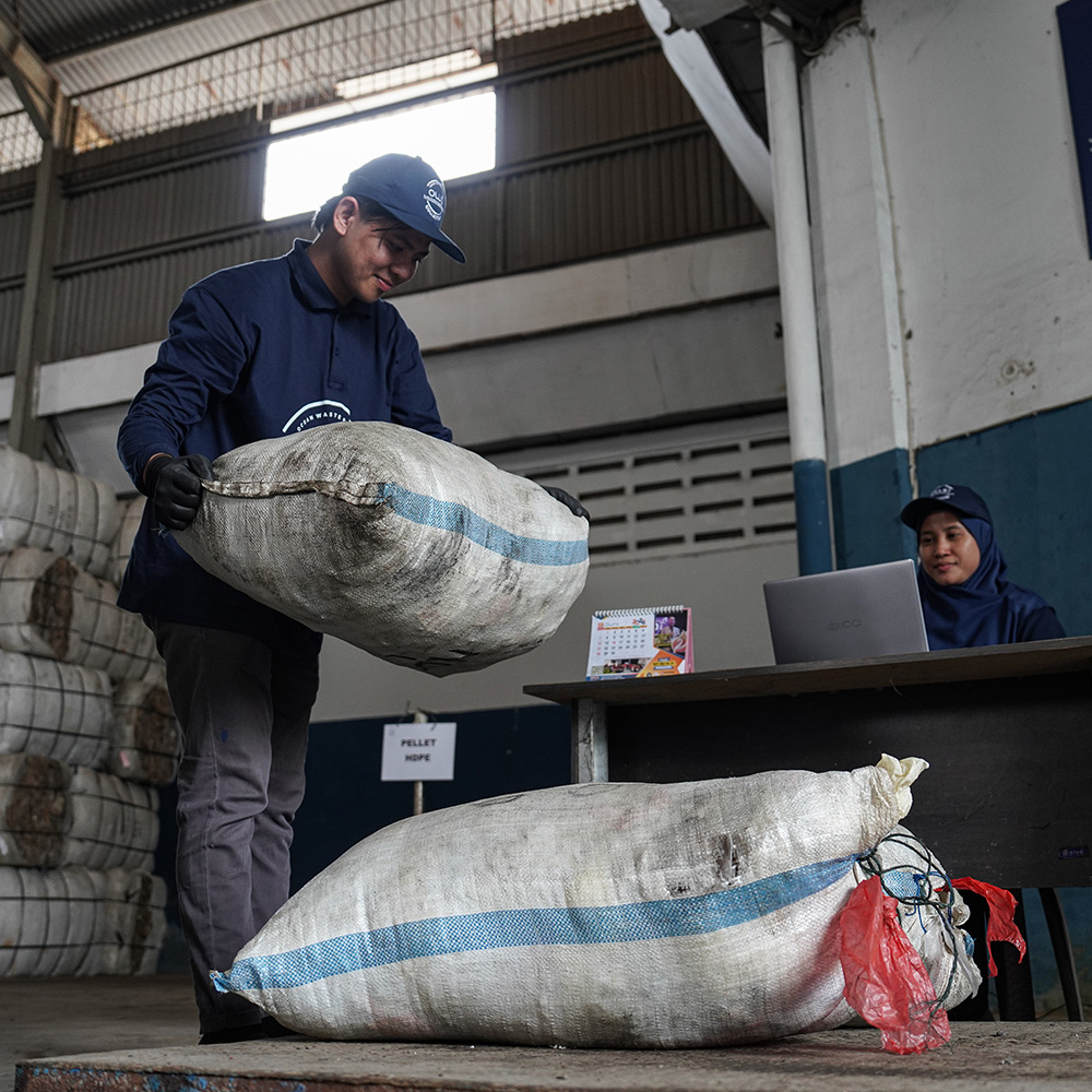 Collector weighing a bag of collected plastic